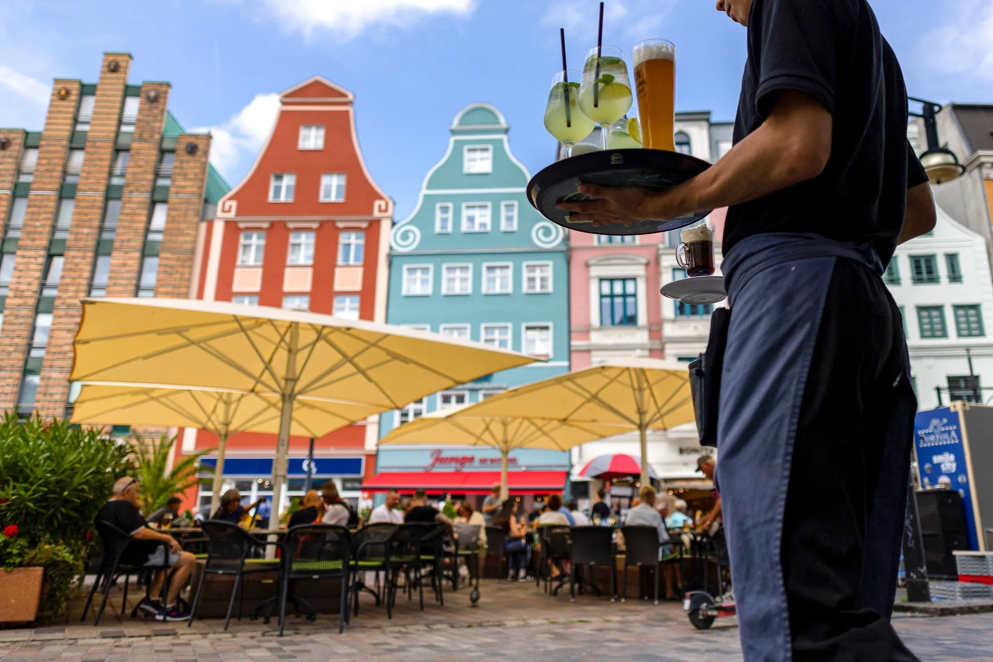 A waiter serves drinks at a restaurant terrace in Rostock, Germany.