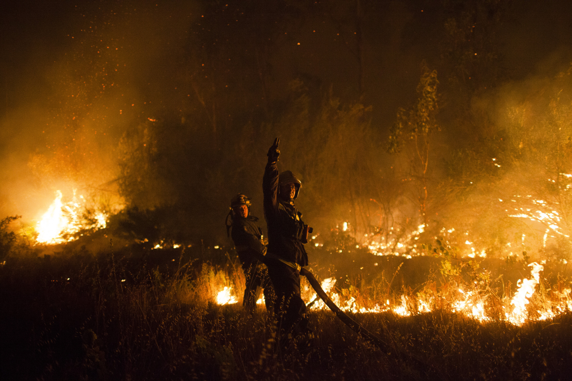 Firefighters work to put out a wildfire at a forest in the town of San Ramon in Constitucion, Chile on Jan. 26, 2017.