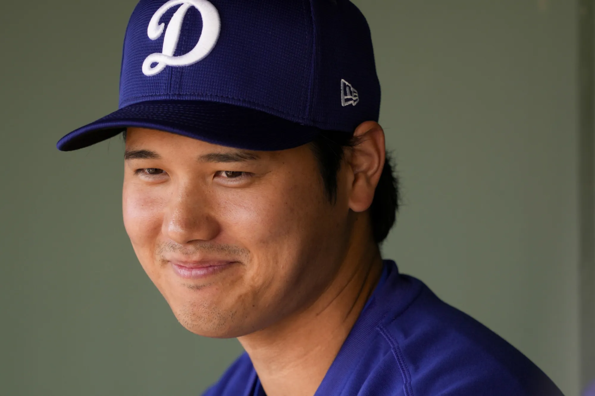 Los Angeles Dodgers designated hitter Shohei Ohtani smiles in the dugout before a spring training baseball game against the Texas Rangers, Wednesday, Feb. 28, 2024, in Surprise, Ariz. (AP Photo/Lindsey Wasson)