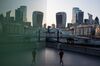 An office building reflects a pedestrian walking along the south bank of the River Thames in view of skyscrapers, including 20 Fenchurch Street, also known as The Walkie Talkie, 22 Bishopgate, The Leadenhall Building, also known as The Cheesegrater, The Scalpel, and 30 St. Mary's Axe, also known as the Gherkin in London, U.K., on Friday, April 24, 2020. The price the U.K. is paying for the coronavirus lockdown is becoming clearer as output shrinks at the fastest pace in decades and the government rolls out a borrowing plan that dwarfs the response to the global financial crisis.