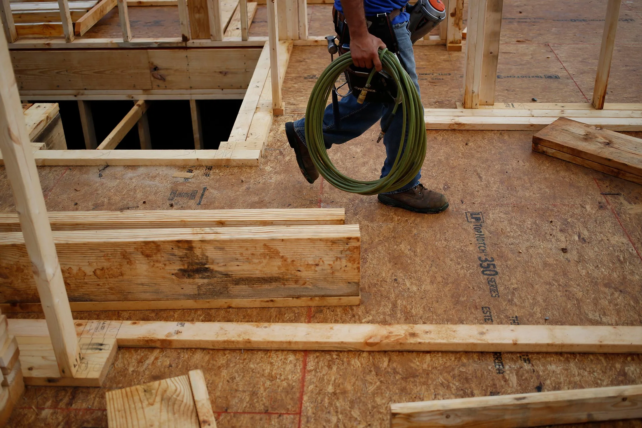 A contractor carries a nail gun while working on a house under construction in the Norton Commons subdivision of Louisville.
