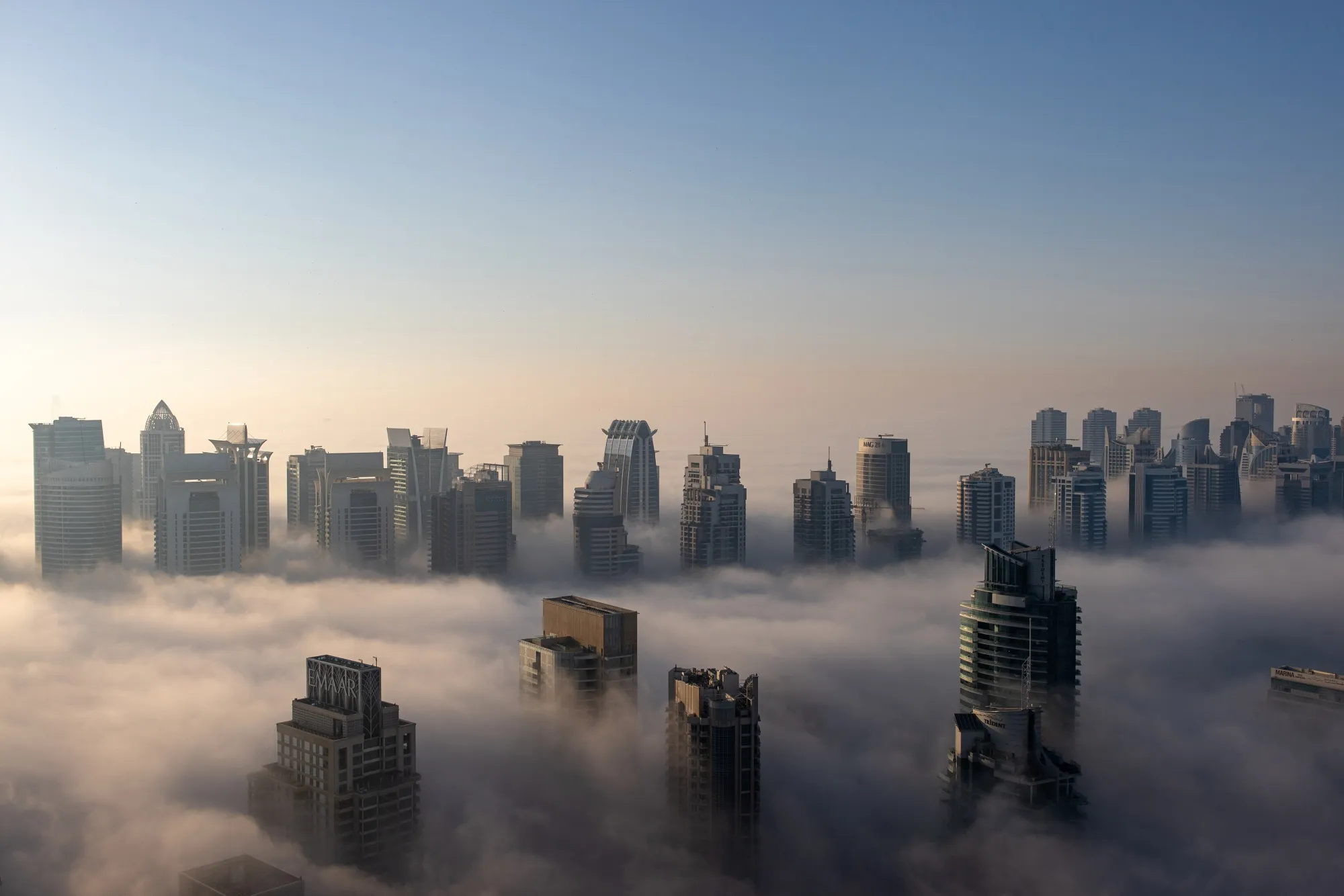 Residential and commercial skyscrapers among morning fog in&nbsp;Dubai.