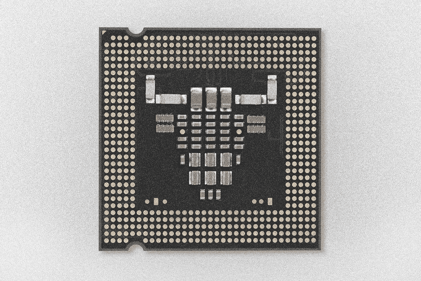 A grainy black and white image of a computer central processing unit, a flat square with circuit pieces in the center that are in the shape of a bull head.