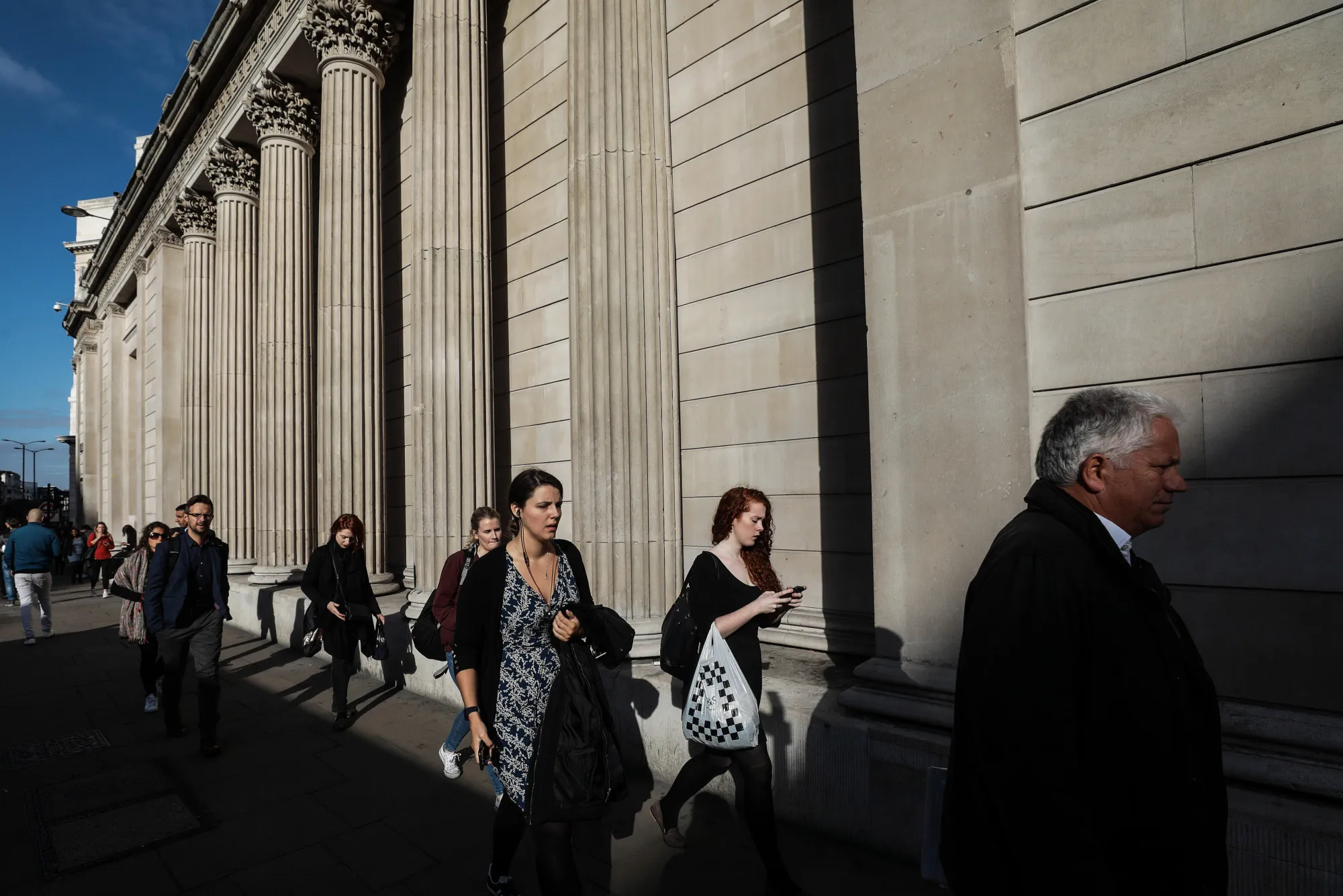 Pedestrians walk past the columns of the Bank of England in London.