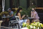 People wearing protective masks sit outside a cafe in the Meatpacking neighborhood of New York, U.S., on Monday, July 6, 2020.