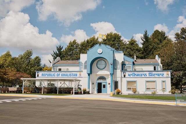 A parking lot and building with a “Republic of Khalistan” banner displayed on one side of the front of the building.
