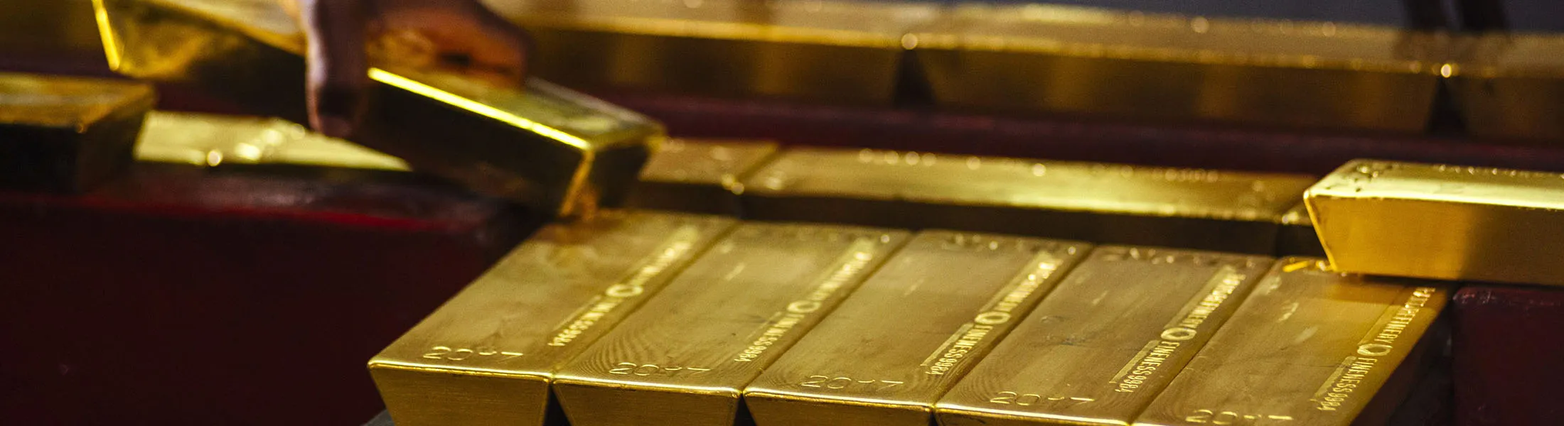 A worker lifts a gold bullion bar from a conveyor machine at the Rand Refinery Ltd. plant in Germiston, South Africa, on Wednesday, Aug. 16. 2017. Established by the Chamber of Mines of South Africa in 1920, Rand Refinery is the largest integrated single-site precious metals refining and smelting complex in the world, according to their website.