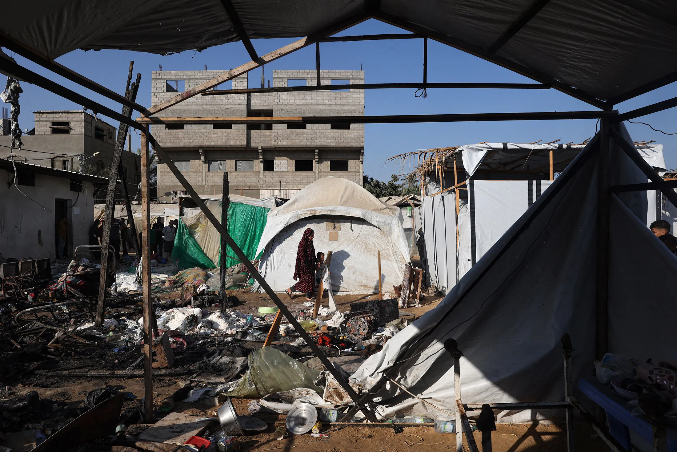 A woman and child walk&nbsp;past destroyed shelters in the aftermath of a reported Israeli strike in the courtyard of the Al-Aqsa Martyrs hospital in Deir el-Balah, Gaza, on Aug.&nbsp;4.