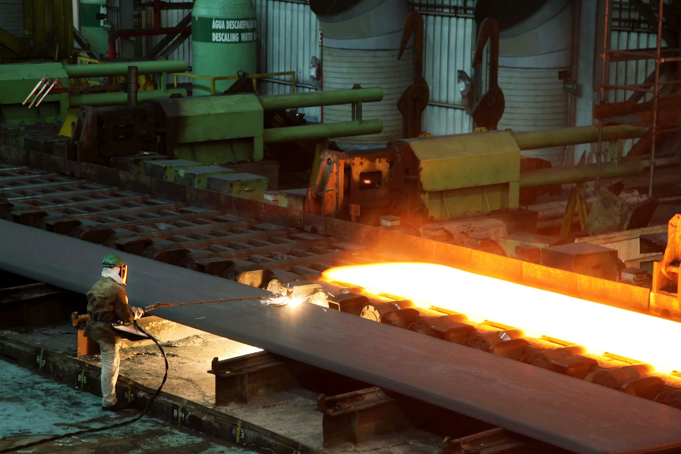 A worker cuts a slab of steel at the ArcelorMittal Brasil SA steel mill in Serra, Espirito Santo, Brazil.