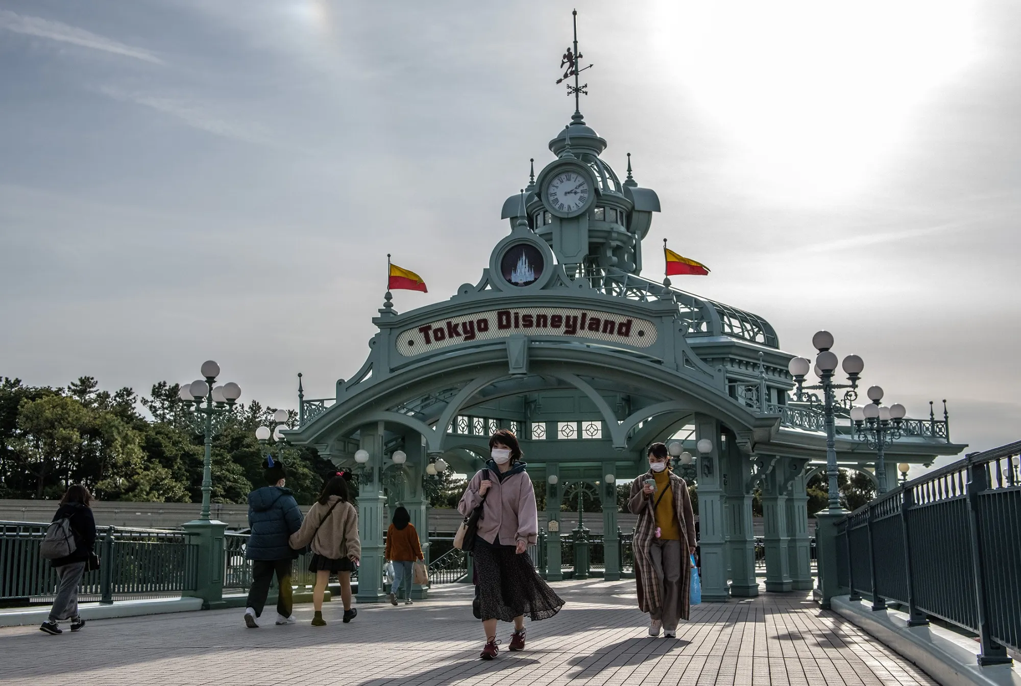 People pass beneath an archway leading to Tokyo Disneyland.