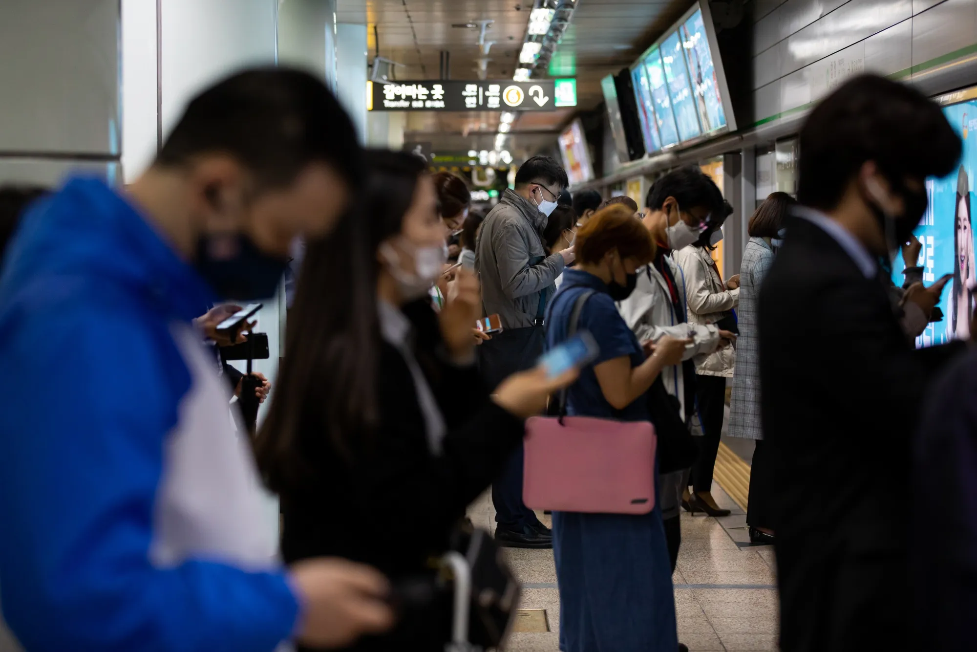 Passengers wearing protective masks wait in line on a platform inside a subway station in Seoul on May 18.
