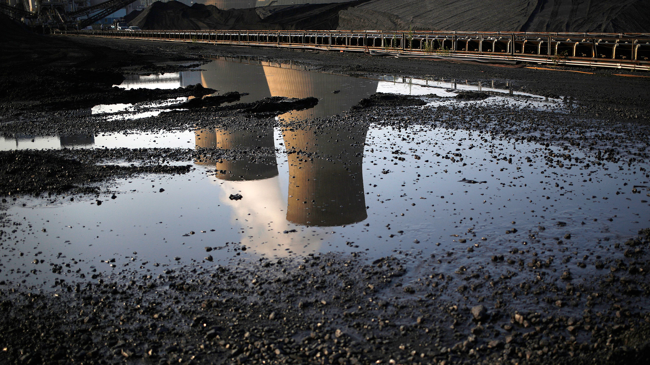 Cooling towers are reflected in a puddle in Winfield, West Virginia.
