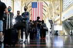 Travelers wearing protective masks stand in line at Ronald Reagan National Airport.