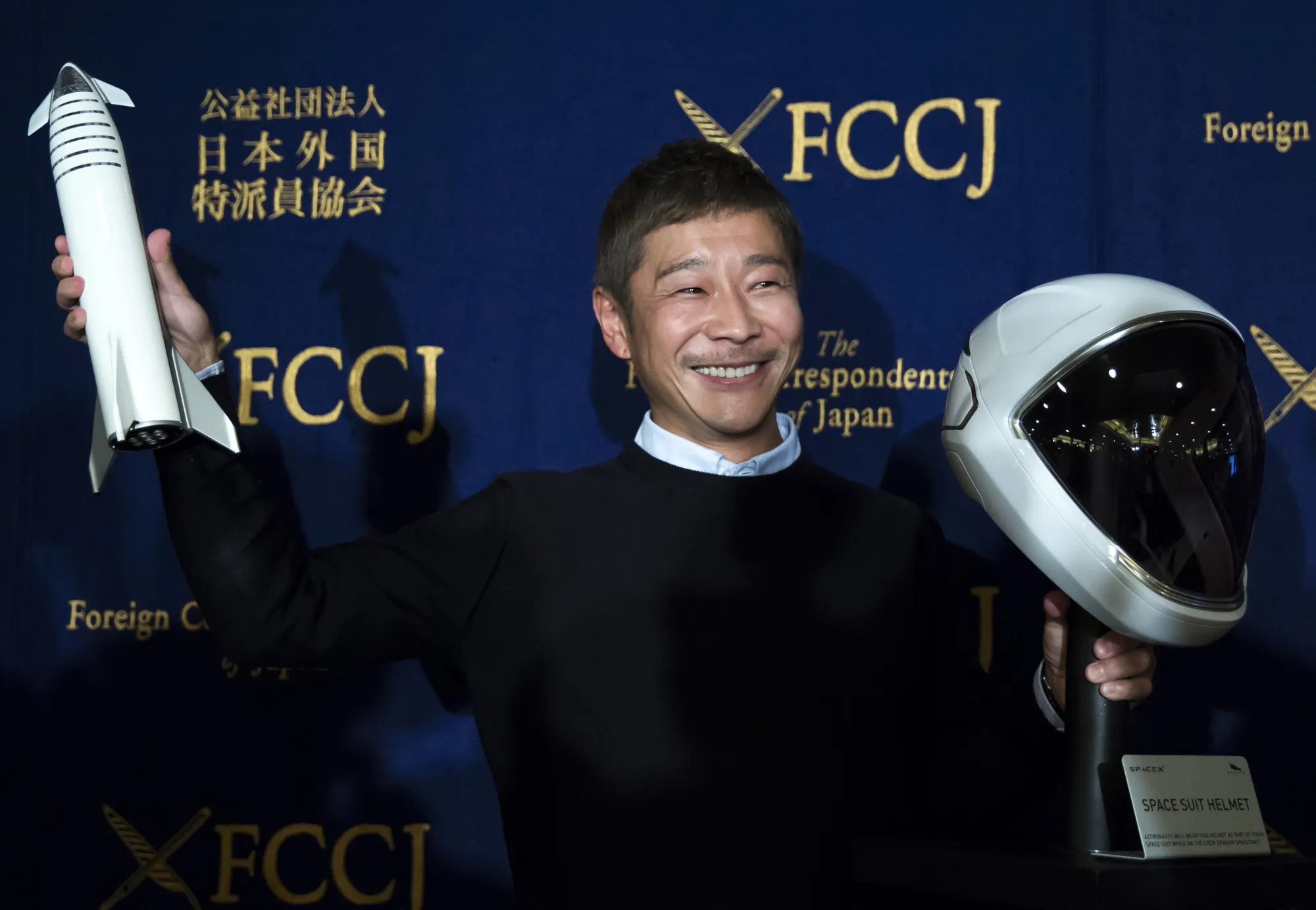 Yusaku Maezawa poses with a model of the SpaceX BFR rocket and the spacesuit's helmet during a news conference at the Foreign Correspondents' Club of Japan in Tokyo, Japan, on Tuesday, Oct. 9, 2018.