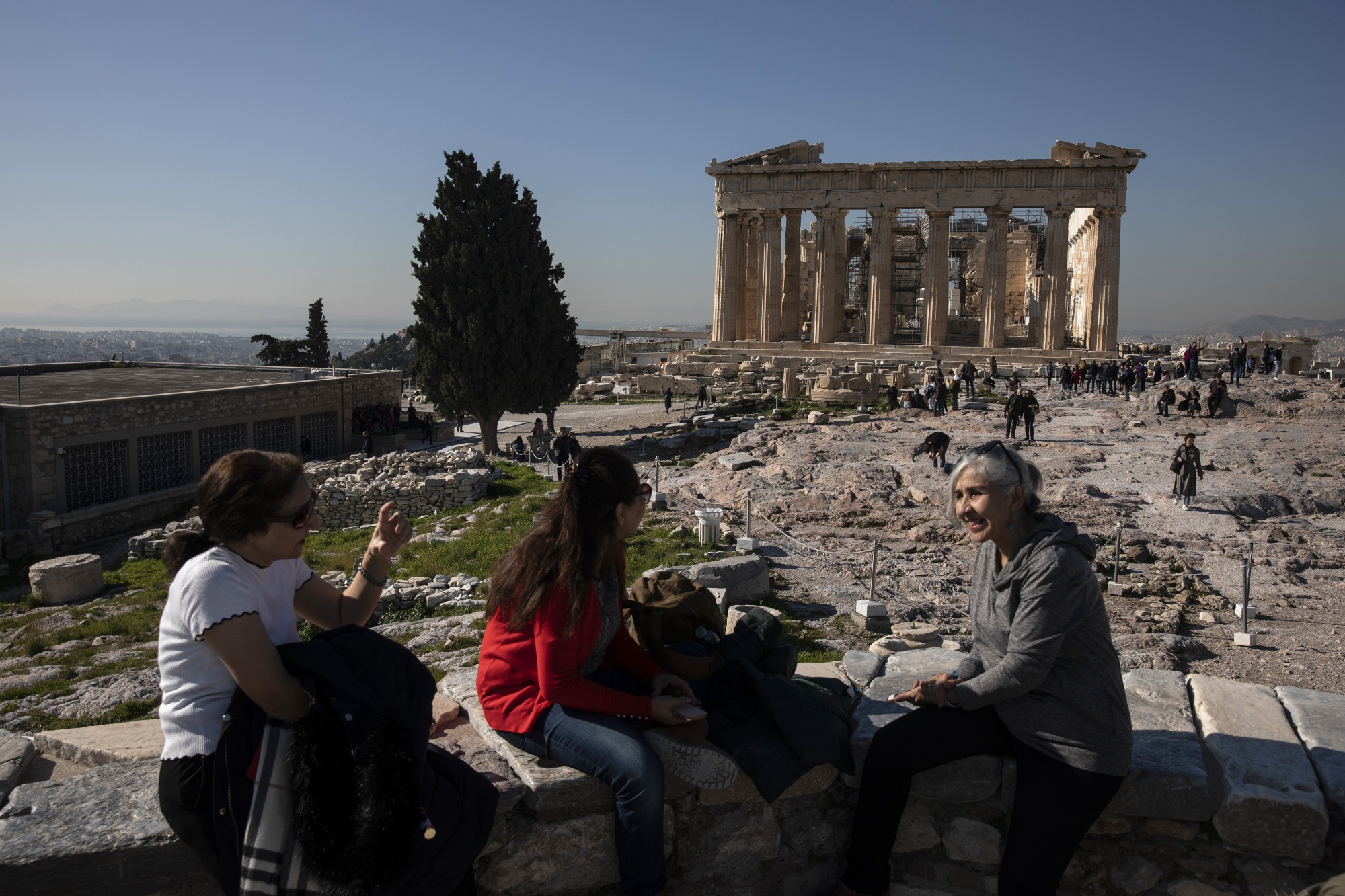 Tourists sit in front of the Parthenon temple on Acropolis Hill in Athens.