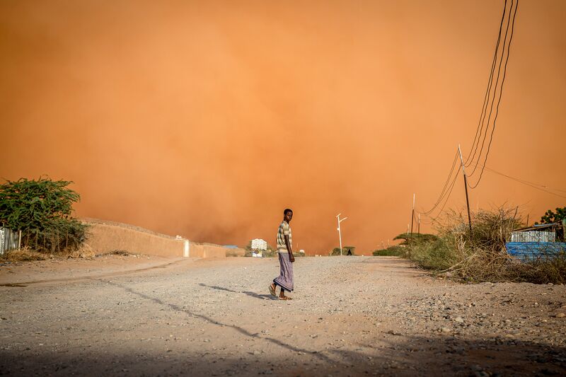 A man walks in front of a sandstorm in Dollow, southwest