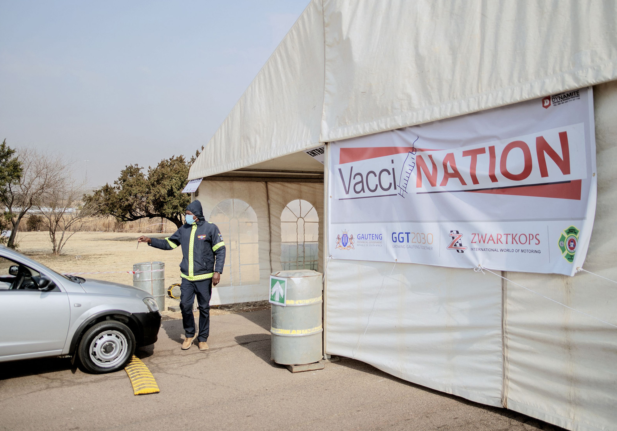 A volunteers directs vehicles into a&nbsp;Zwartkops Raceway drive-through vaccination site, in Centurion, South Africa.