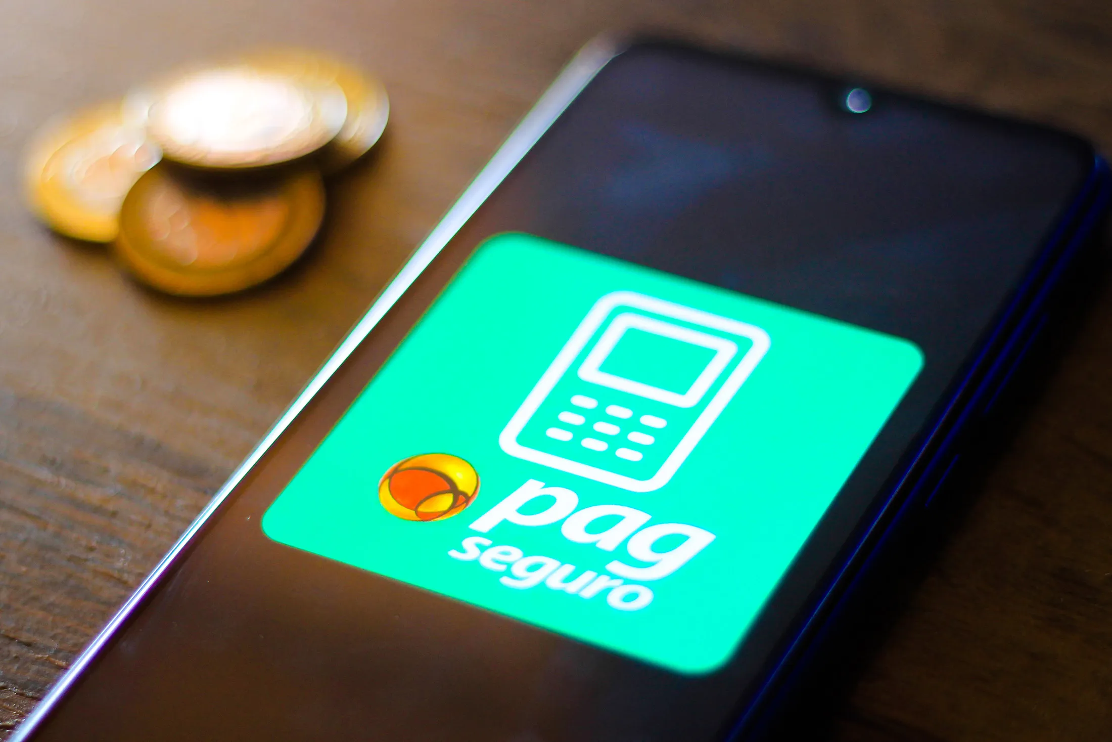 The PagSeguro logo is seen displayed on a smartphone.