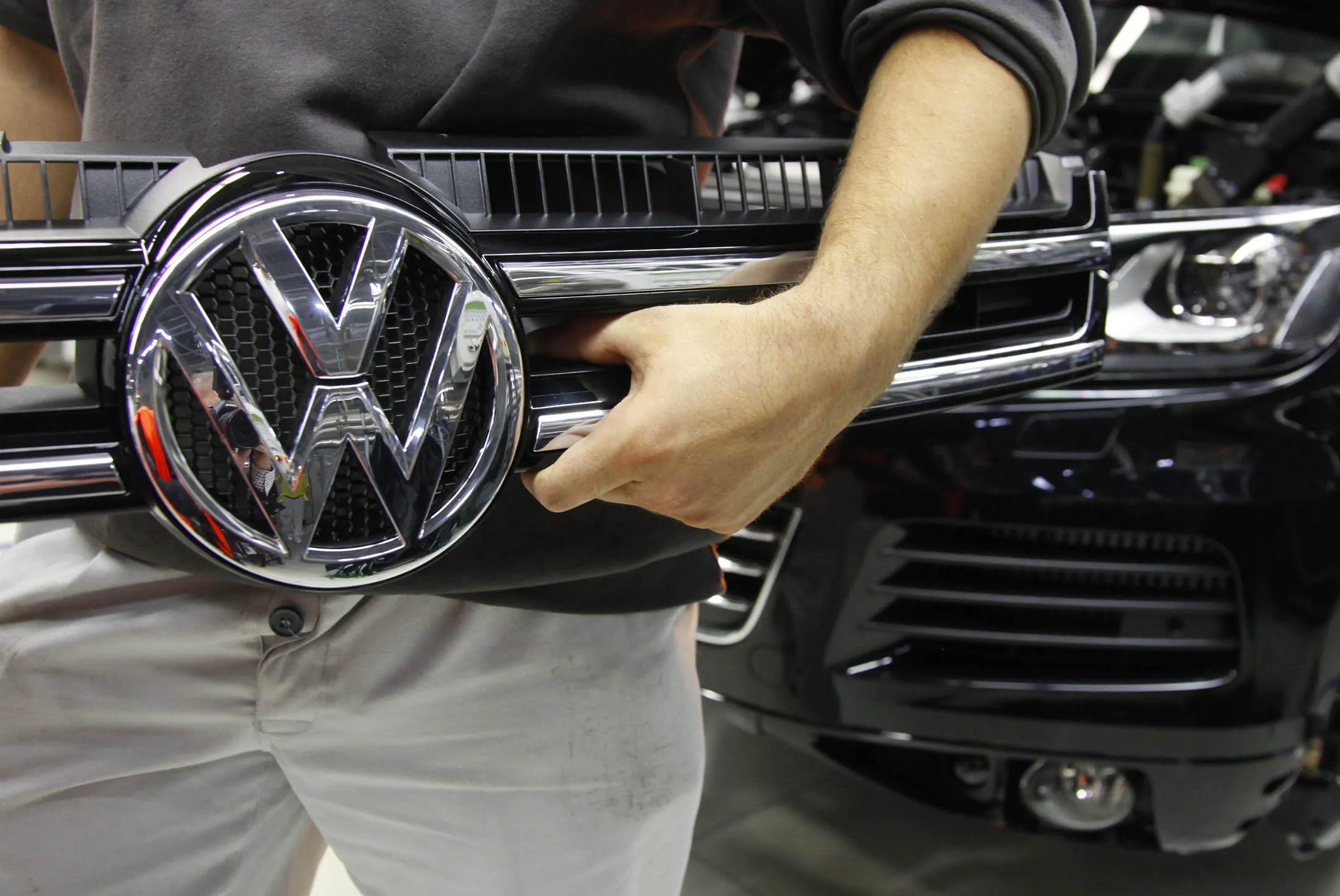 An employee carries the radiator grille of a VW Touareg sport-utility vehicle at the Volkswagen AG (VW) factory in Slovakia.
