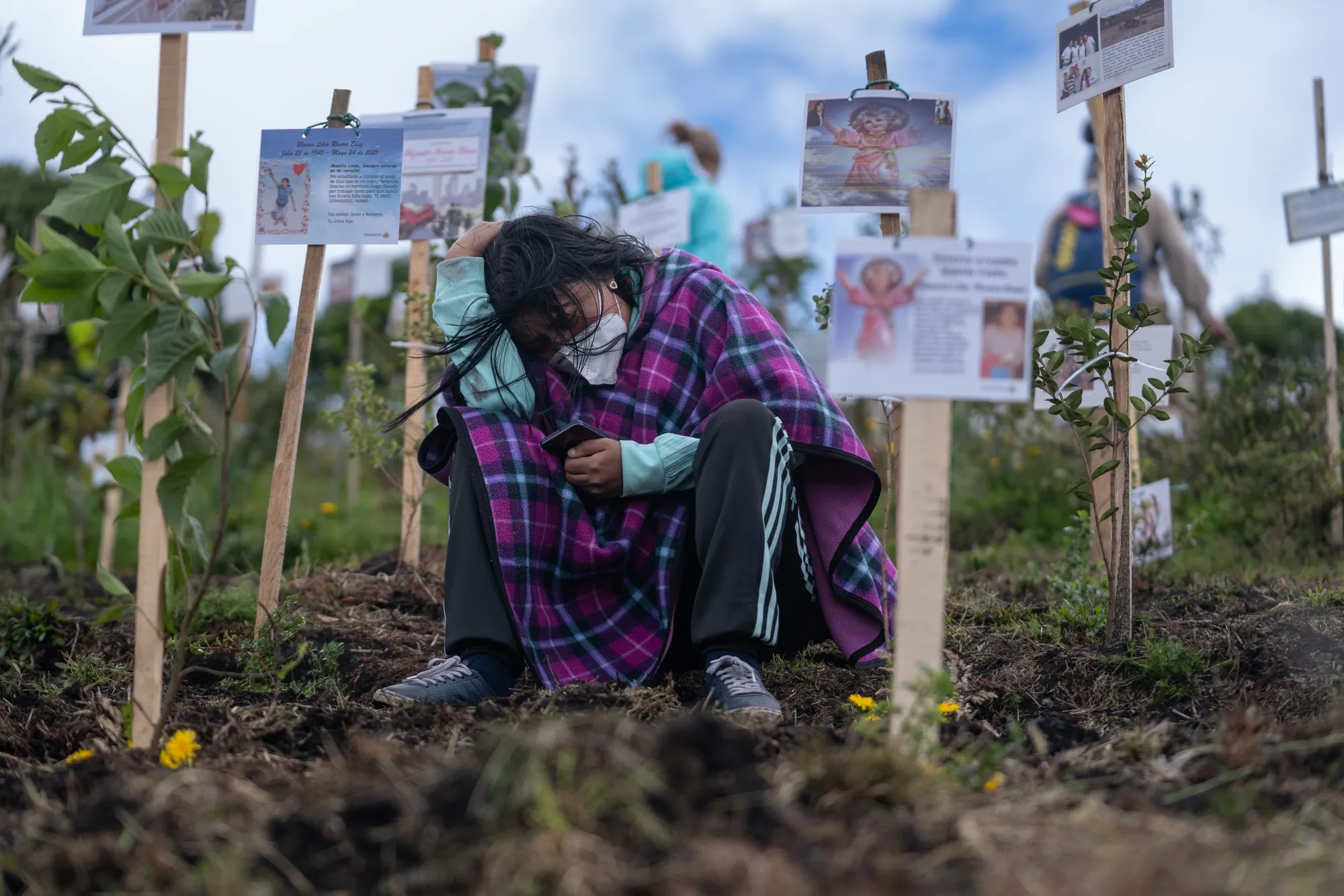 A mourner grieves over the scattered ashes of a Covid-19 victim at a nature preserve in Colombia, which has reported over 118,000 virus-related deaths.