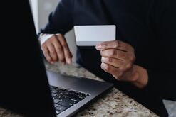 Woman Holds Credit Card While Shopping Online With Laptop