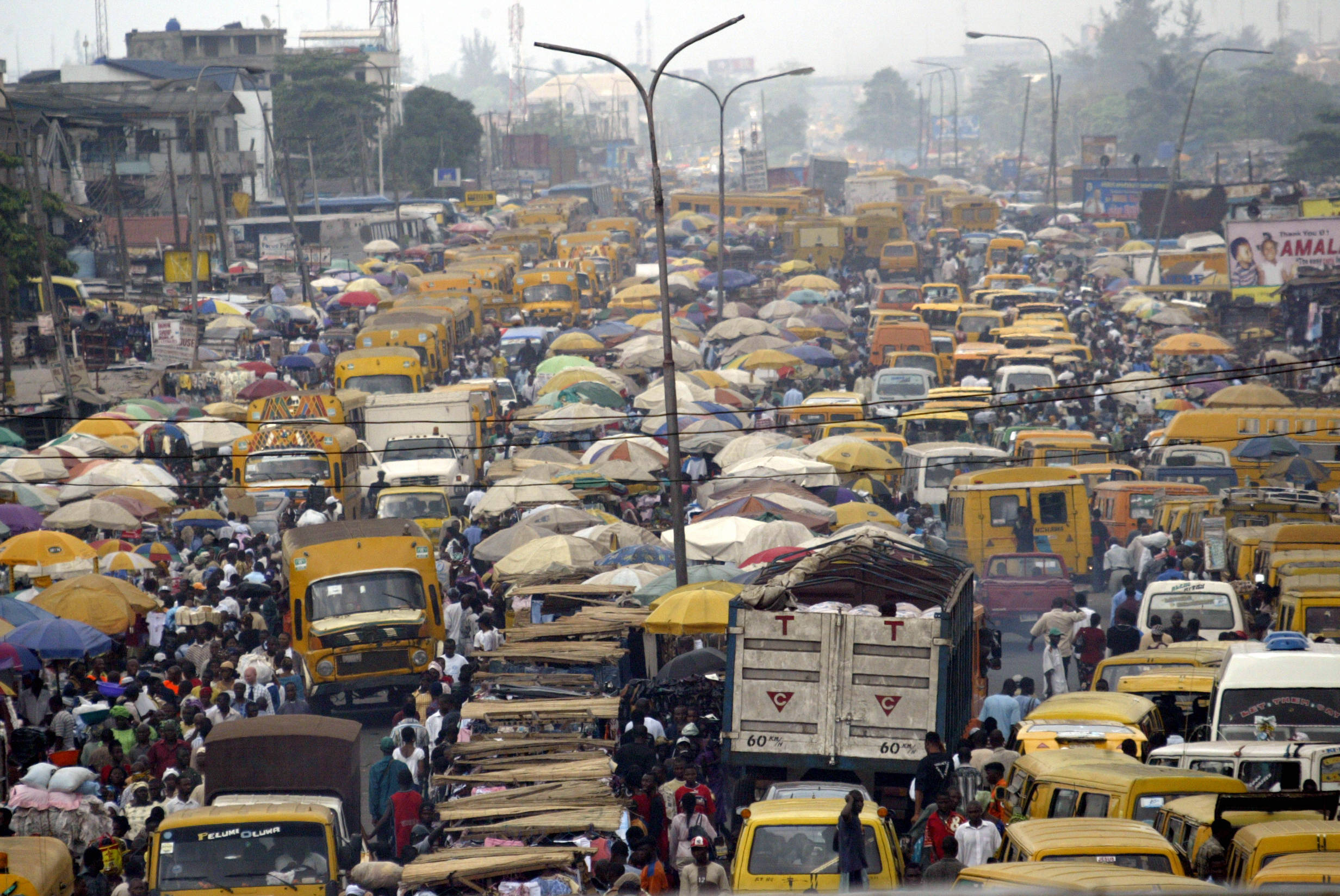 People walk struggling for space between public transport buses and trucks at the burstling Oshodi bus stop in Lagos 06 February 2006. Lagos is reputed as one of the mostly densely populated city in the world with population more than 14 million. AFP PHOTO/PIUS UTOMI EKPEI (Photo credit should read PIUS UTOMI EKPEI/AFP via Getty Images)