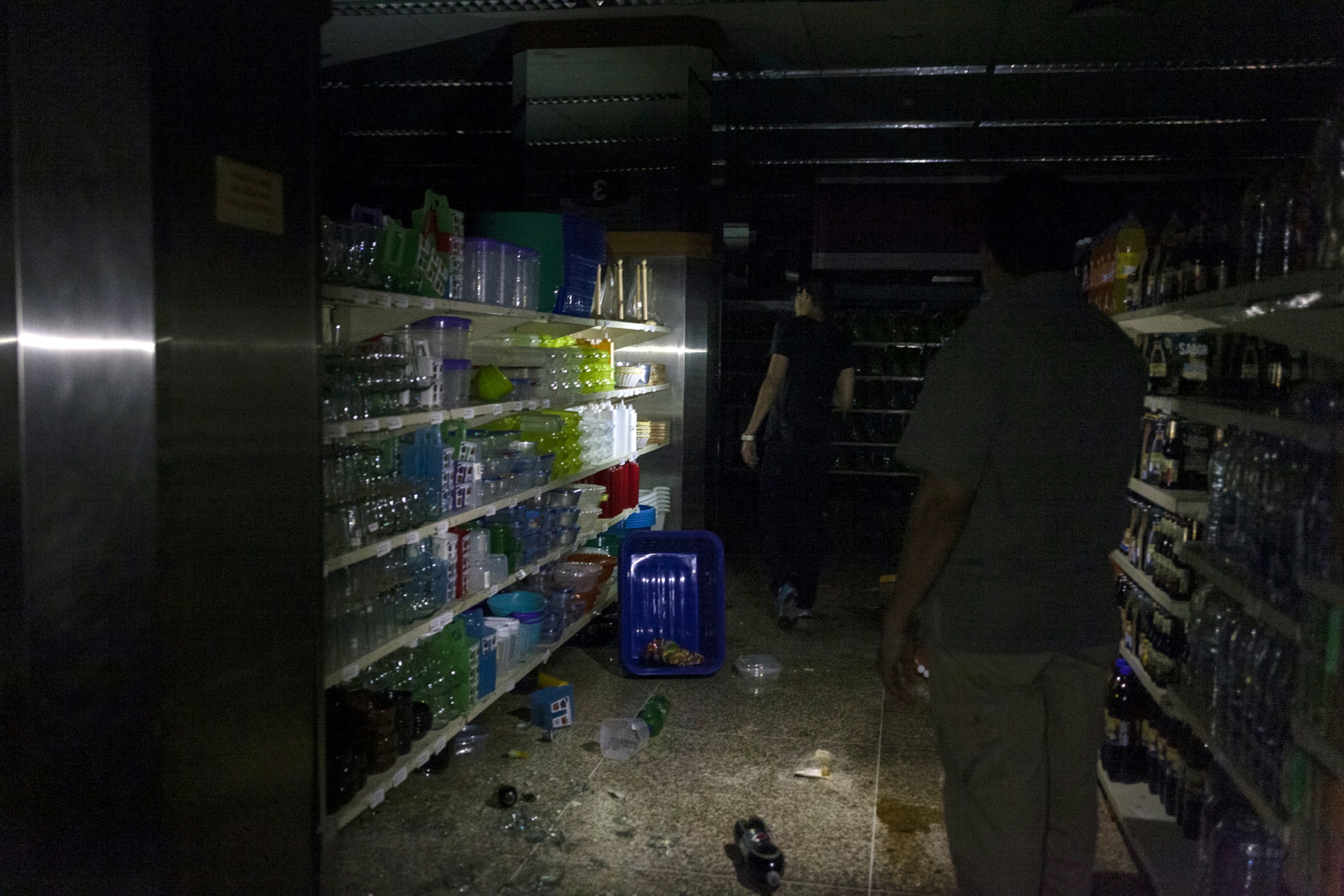 Broken items lie on the floor of a looted supermarket during a continued power outage in Santa Cruz del Este, Caracas on March 10, 2019.