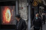 People walk past a Bitcoin symbol at the entrance of a cryptocurrency exchange office in Istanbul, Turkey. 