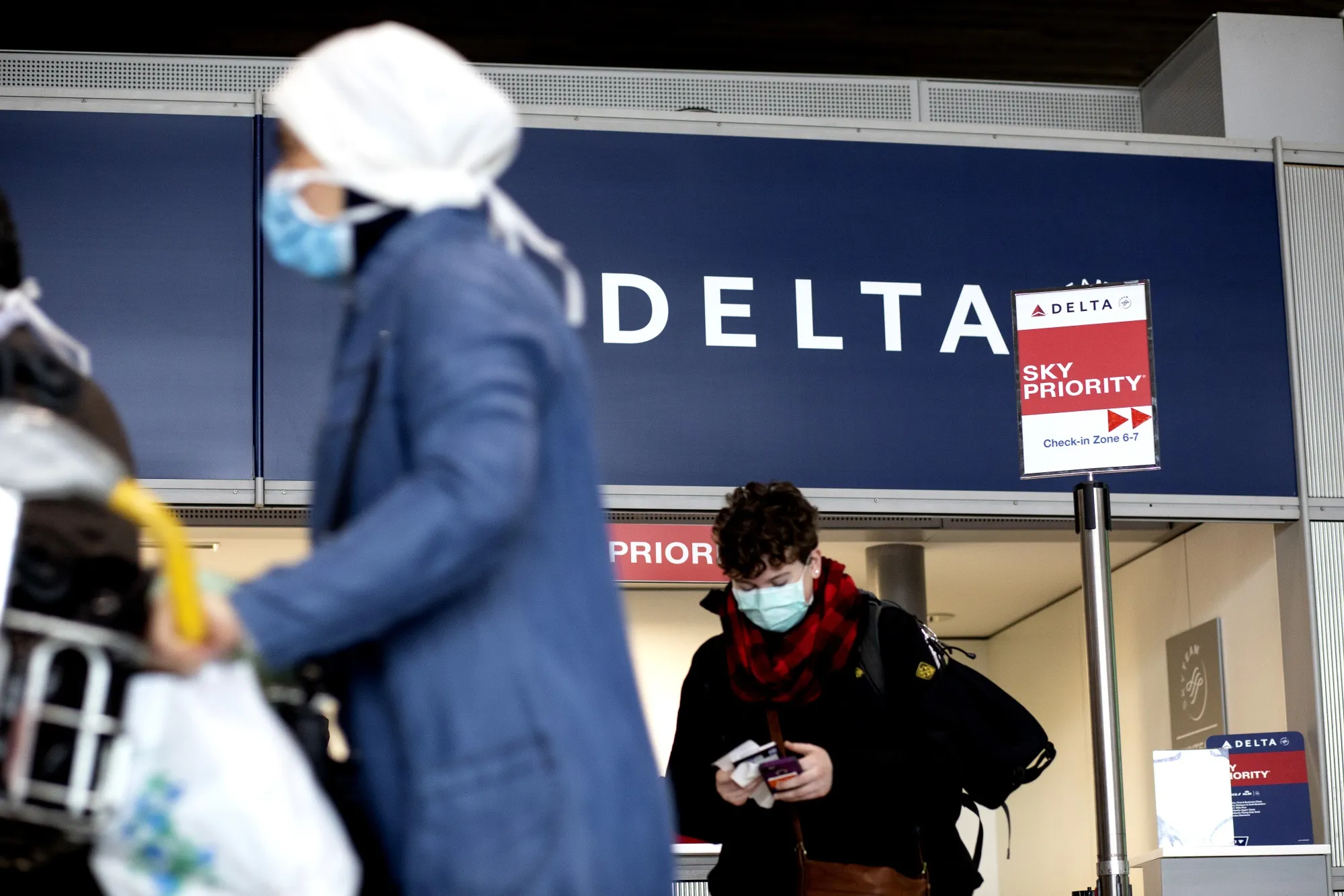 Travelers wearing face masks wait at a Delta Air Lines Inc. customer service desk at Charles de Gaulle Airport,&nbsp;in Roissy, France, on&nbsp;March 16.&nbsp;