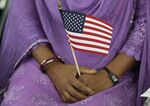 A South Asian woman holds an American flag during a naturalization ceremony in Indianapolis.