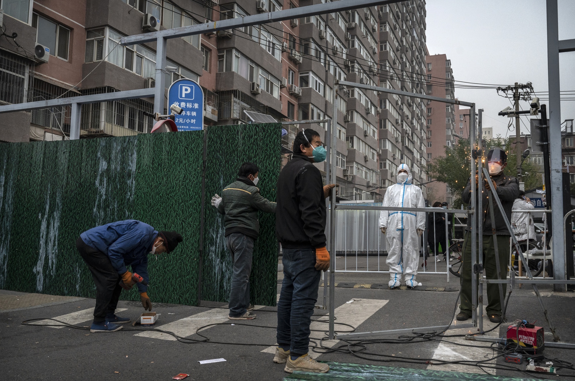 Workers erect a metal barrier outside a community under lockdown in Beijing on Nov. 24.