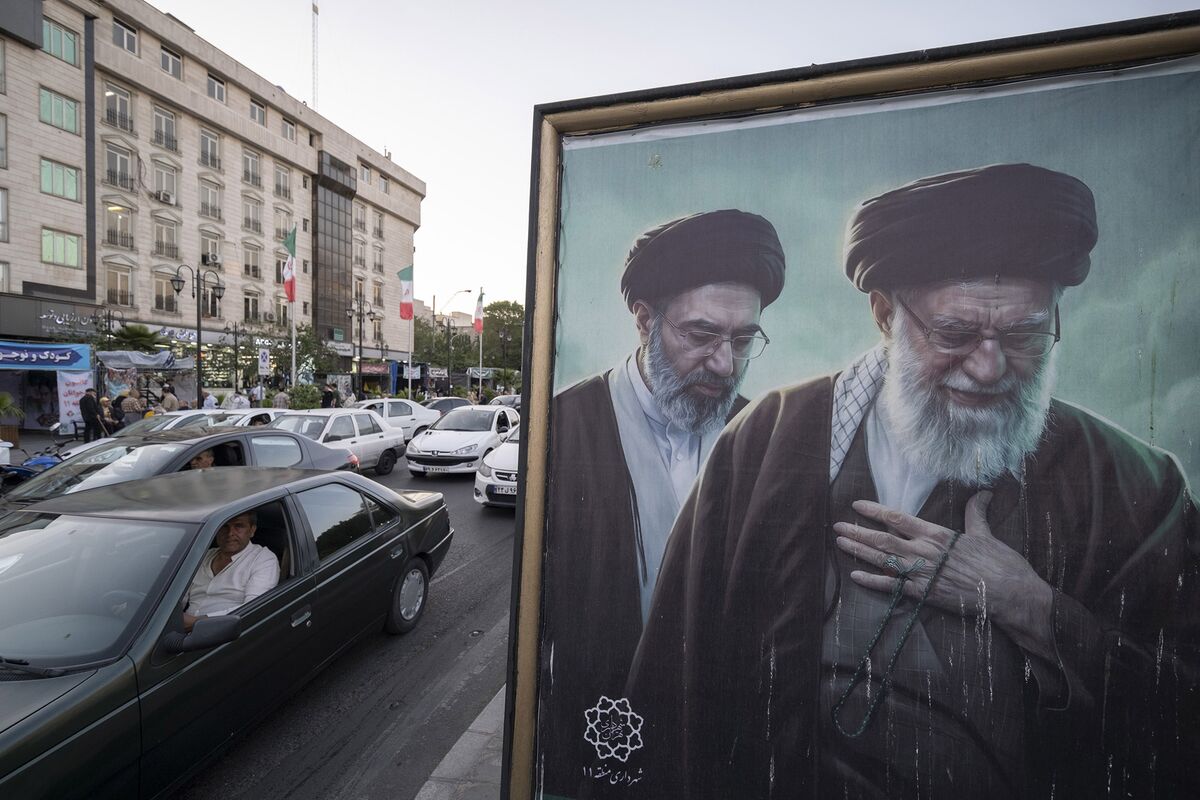 خودروها در حال عبور از کنار تصاویر آیت‌الله علی خامنه‌ای رهبر فقید و آیت‌الله مجتبی خامنه‌ای رهبر جدید ایران در یک منطقه تجاری در مرکز شهر تهران، ایران، در تاریخ ۲۲ مه هستند. عکاس: مرتضی نیکوبذل/نورفوتو/گتی ایمیجز