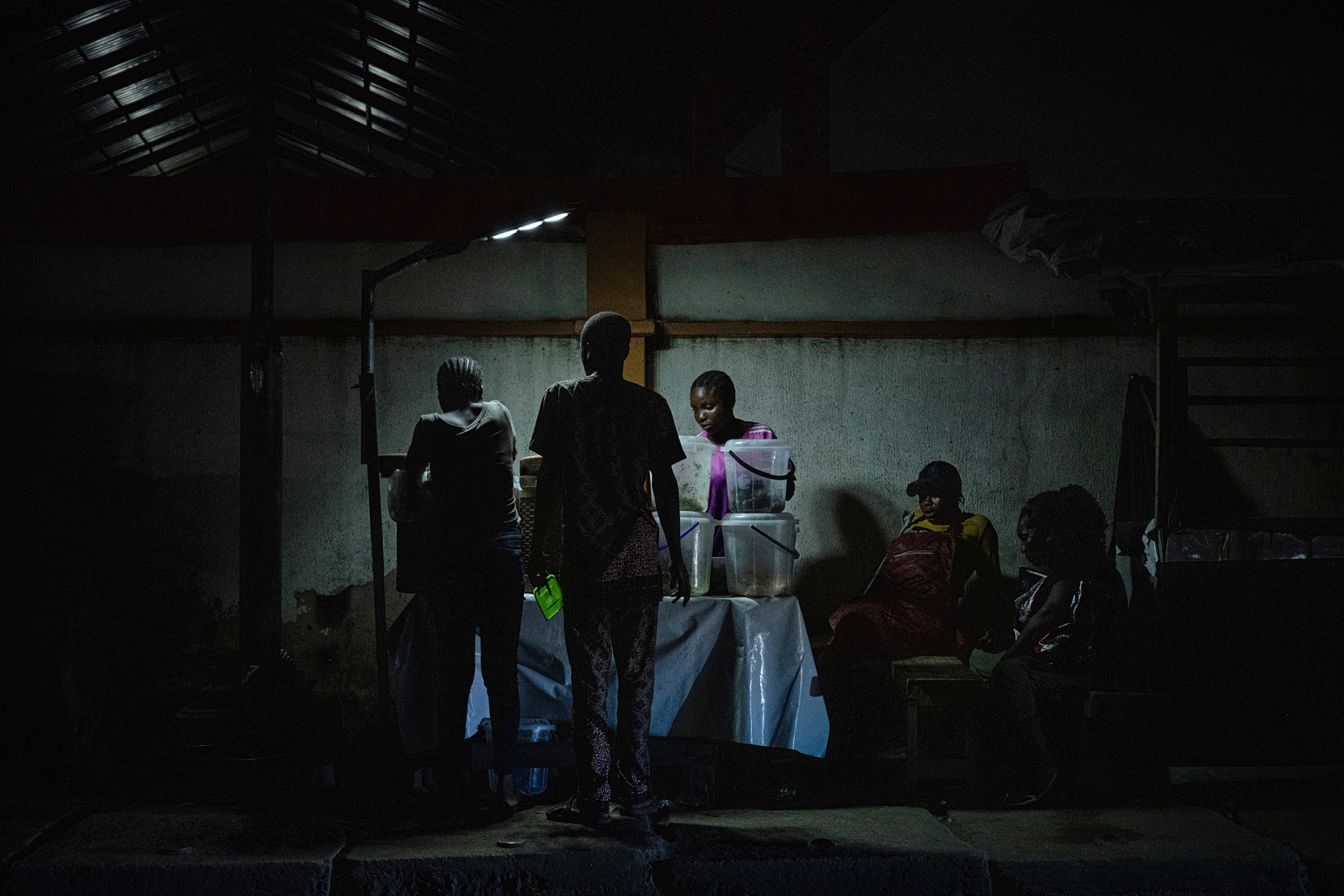People gathered around a small food stand lit by a single security light during a power outage in Lagos, Nigeria.