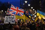 People stand with placards and Ukrainian and Union flags at a demonstration in central London.