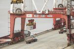 Container trucks move past gantry cranes at the Yangshan Deep Water Port in Shanghai, China.