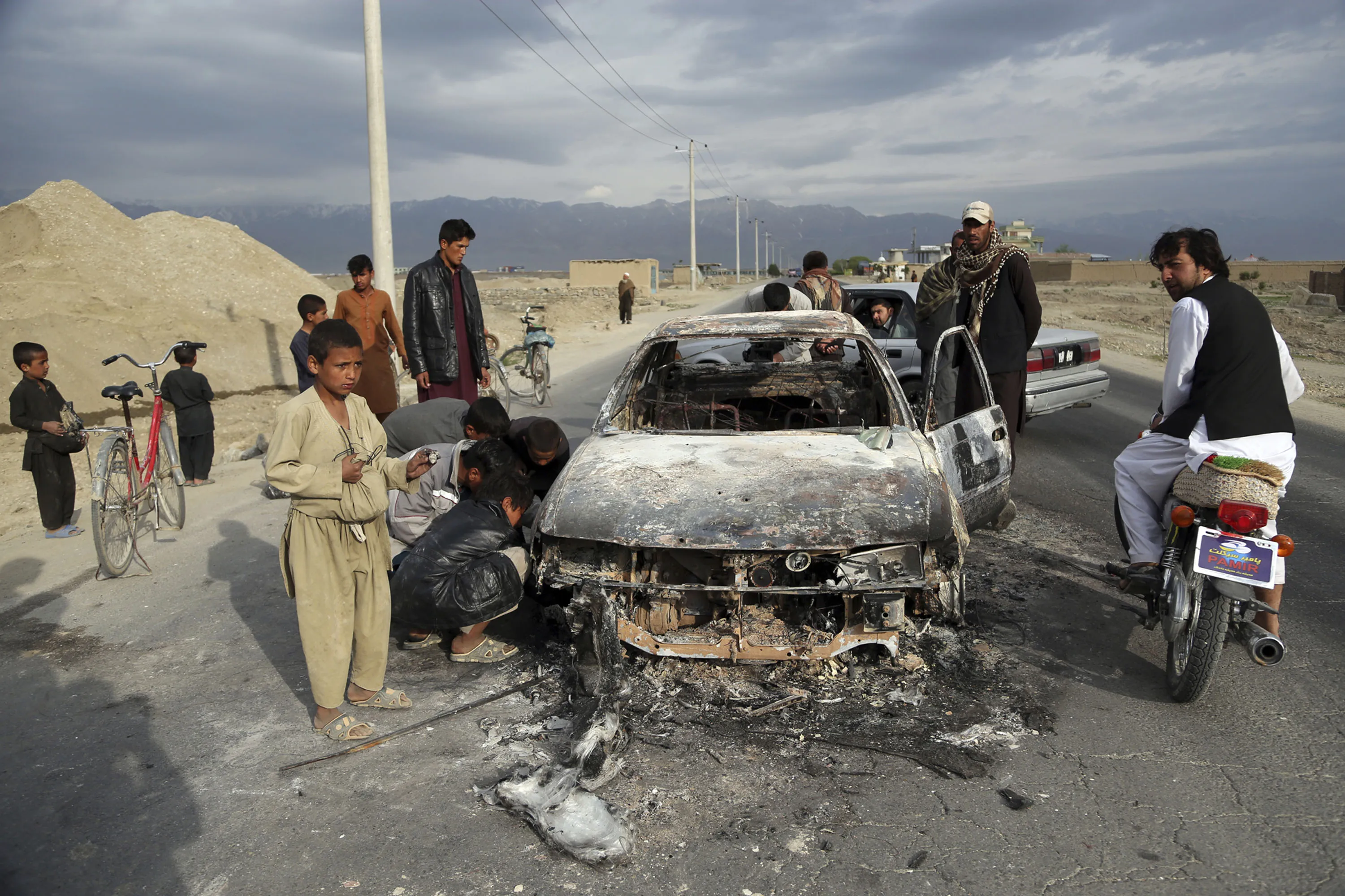 Afghans watch a civilian vehicle burnt after being shot by US forces after an attack near the Bagram Air Base, Afghanistan, April 9.