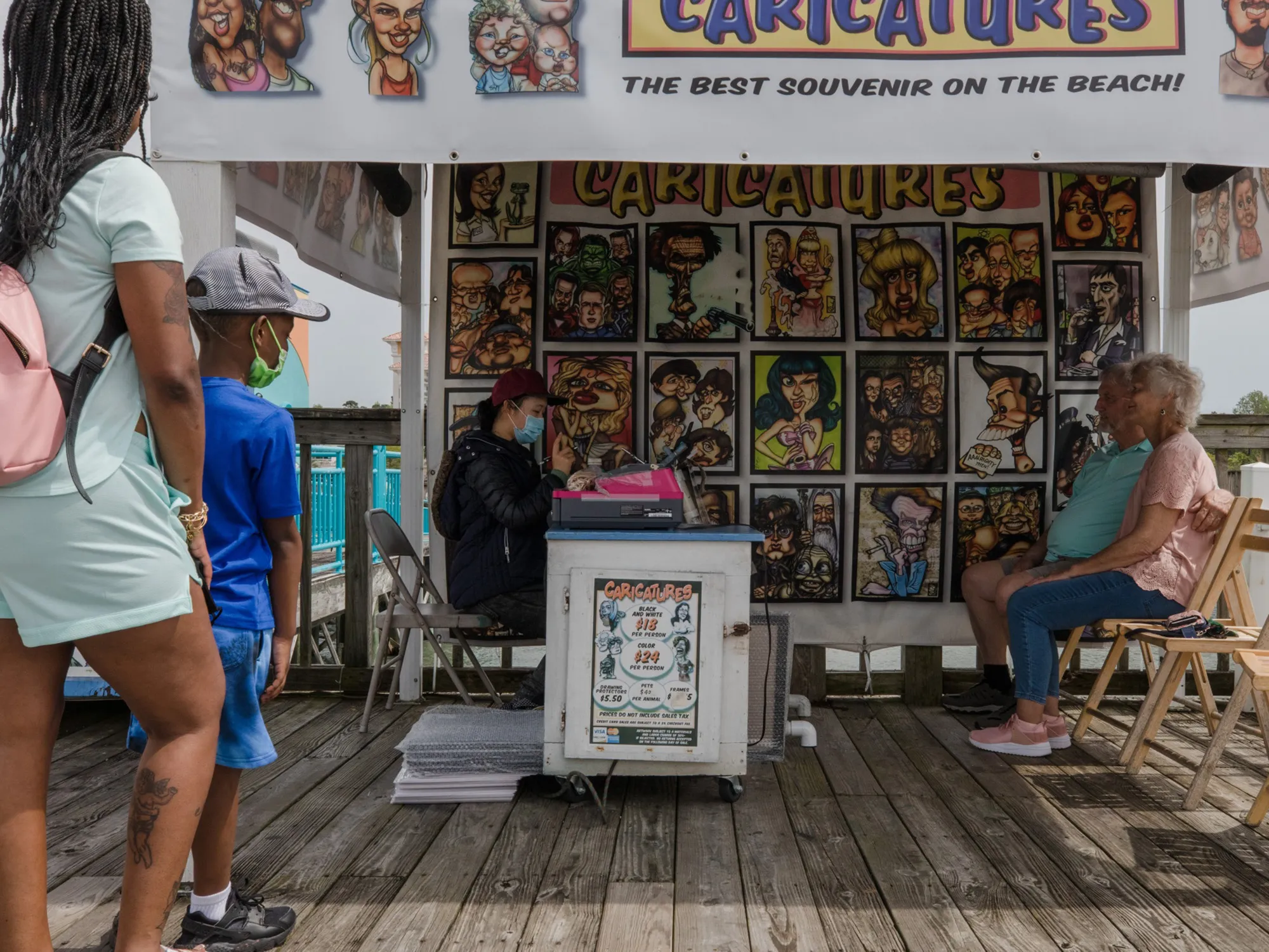 A caricature artist draws the image of a couple while customers wait in line at a vendor stall at Broadway at the Beach in Myrtle Beach, South Carolina.