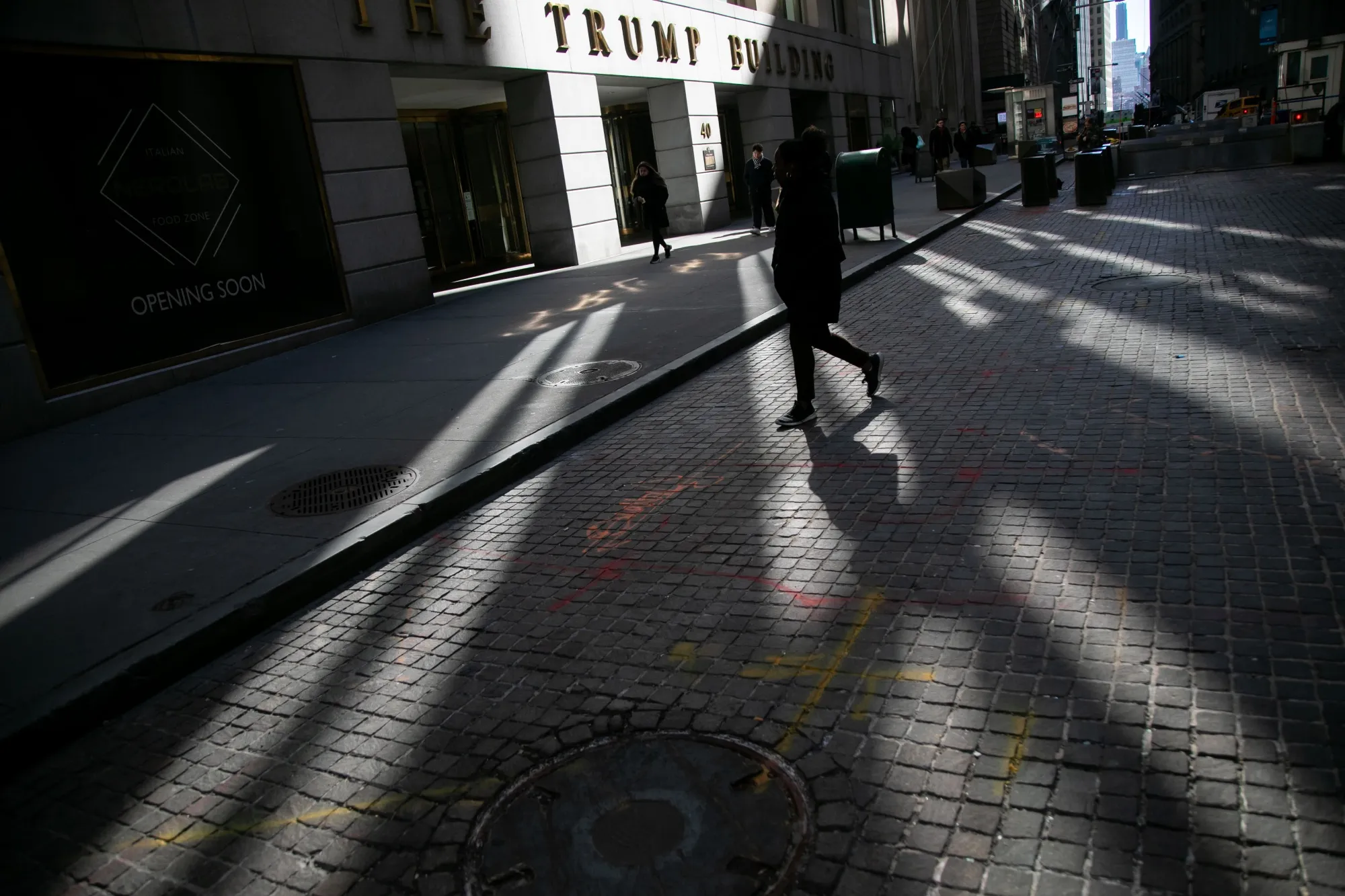 Pedestrians walk along Wall Street in front of The Trump Building near the New York Stock Exchange.