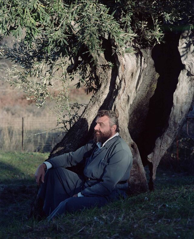 Father Christos, an olive-growing priest sits under a tree