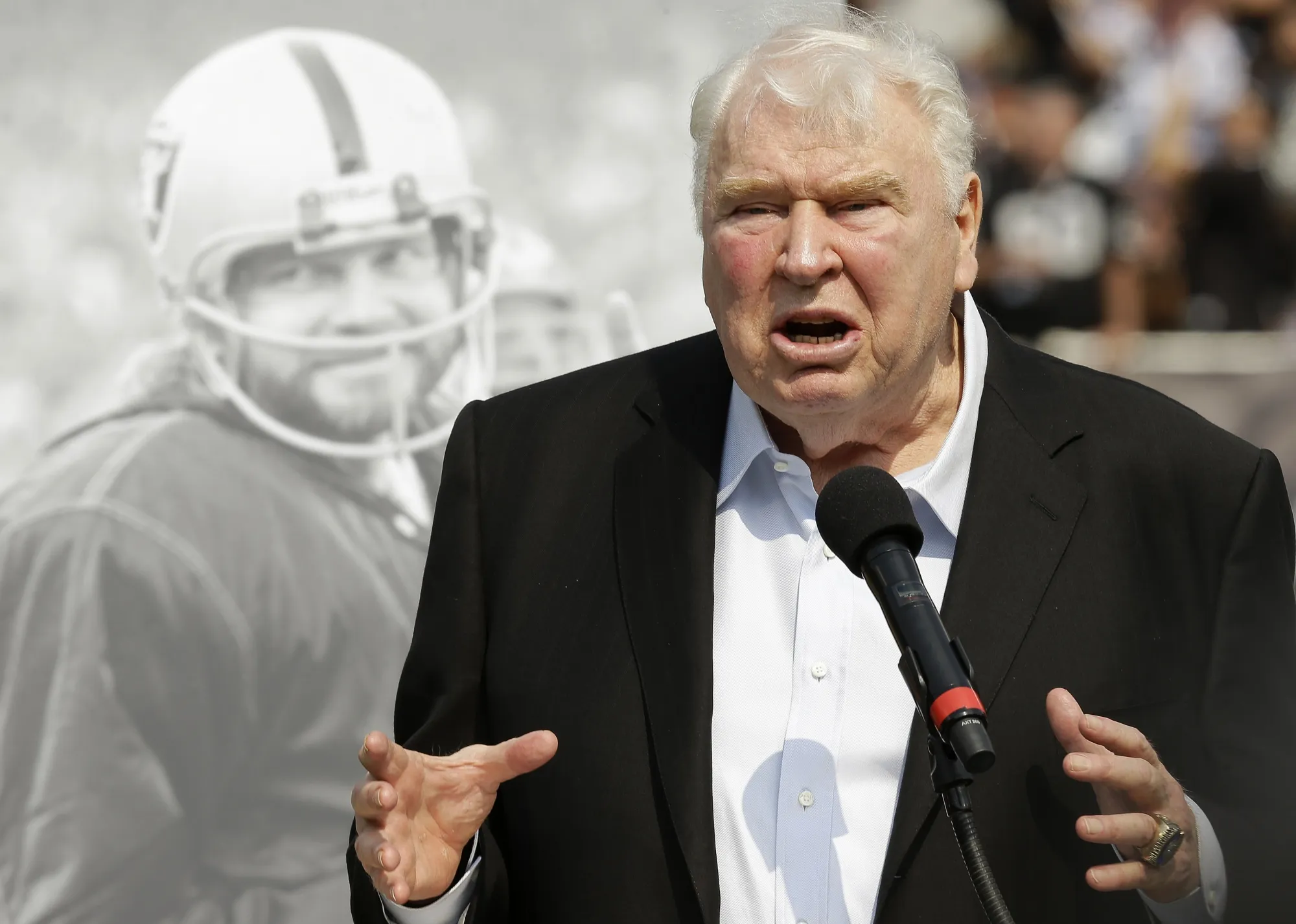 Former Oakland Raiders head coach John Madden speaks about former quarterback Ken Stabler, pictured at rear, at a ceremony honoring Stabler during halftime of an NFL football game between the Raiders and the Cincinnati Bengals in Oakland, Calif., on Sept. 13, 2015.  'All Madden' documentary a labor of love for Fox Sports. Many gamers will be receiving the latest edition of the “Madden” video game for the holidays. On Saturday, Dec. 25, 2021, some will even find out for the first time that the name behind the popular franchise was a successful coach and broadcaster. (AP Photo/Ben Margot, File)