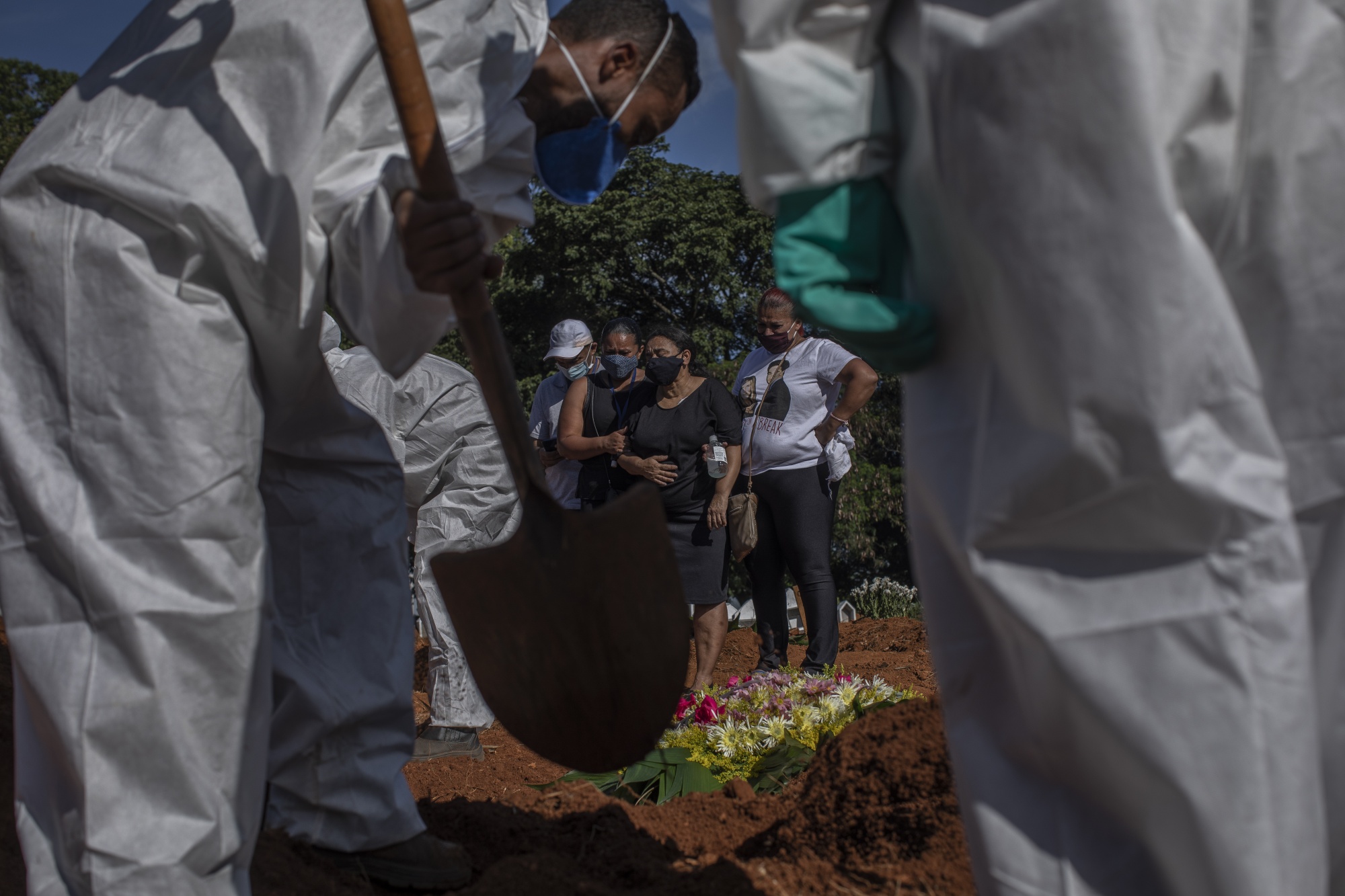 Mourners watch as workers wearing protective equipment bury the casket of a Covid-19 victim at the Vila Formosa cemetery in Sao Paulo, Brazil, on&nbsp;March 24.