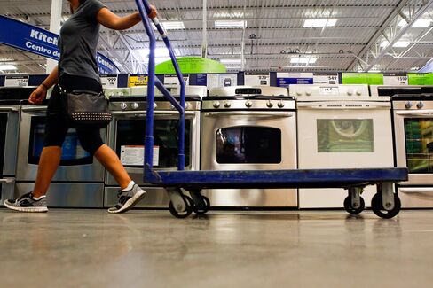A woman pulls a cart past a General Electric Co. gas range home appliance.