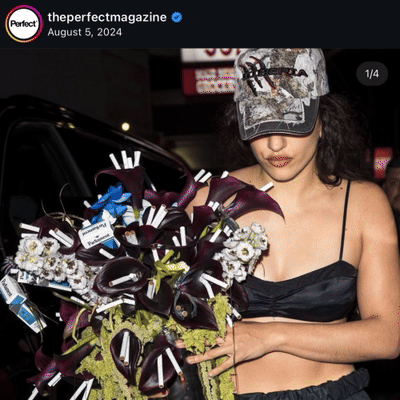 Rosalia's bouquet that has an array of dark purple and blue flowers alongside loose cigarettes and packs of cigarettes.