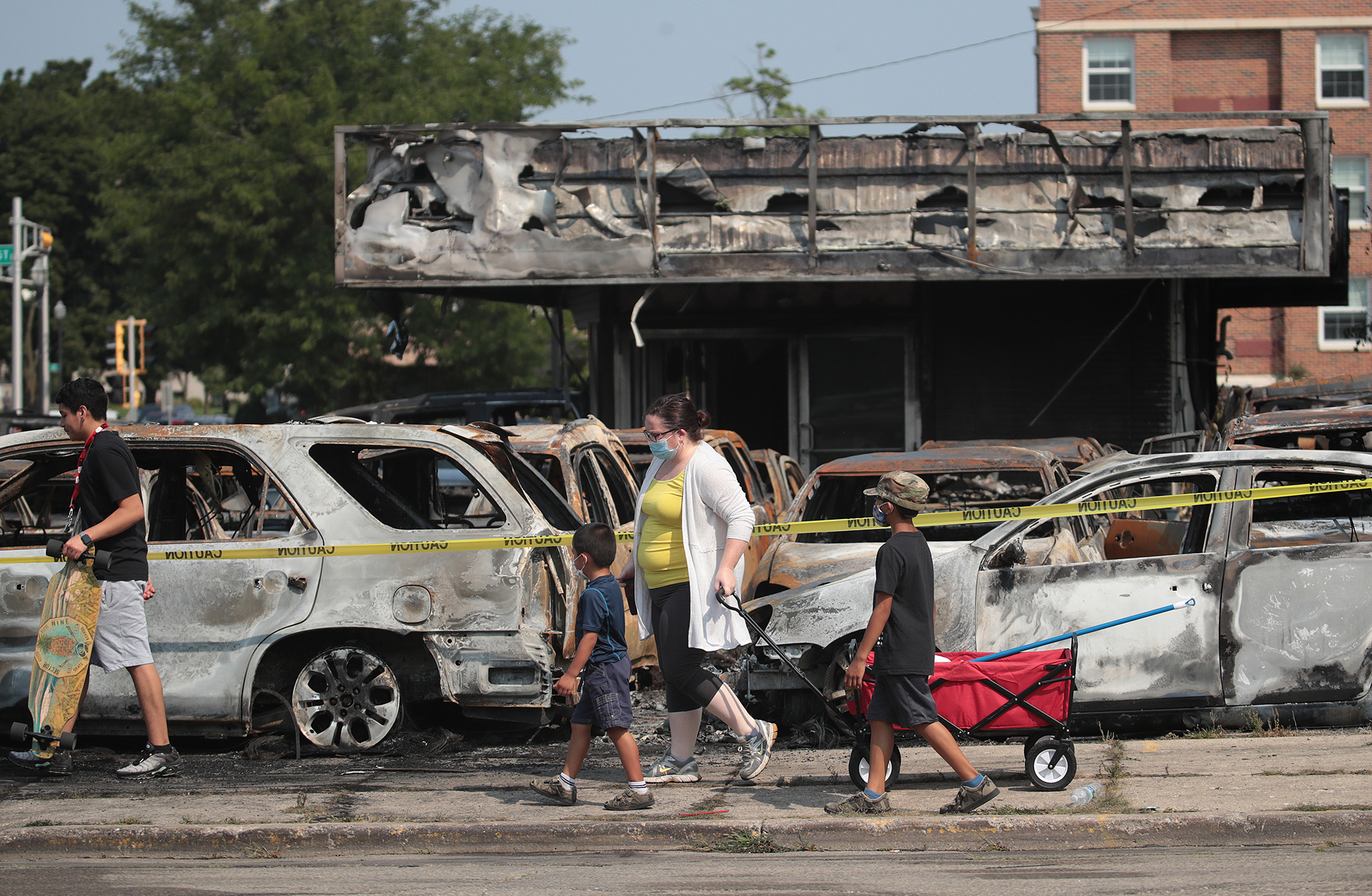 People walk past a lot with burned out used cars after a night of unrest in Kenosha, Wisconsin, on Aug.&nbsp;24.