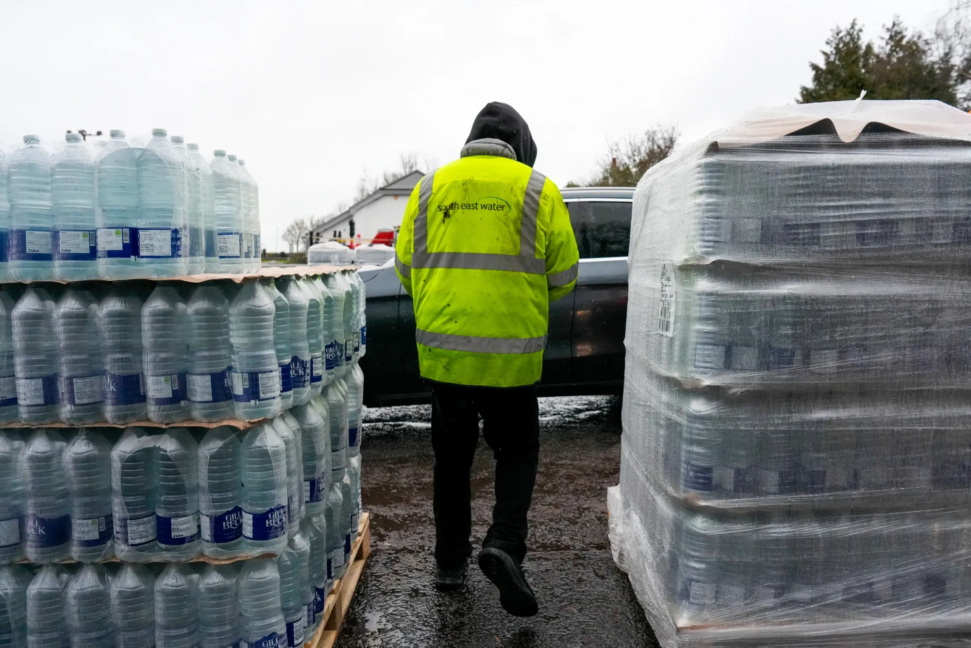 An employee of South East Water Ltd. fills cars with water bottles at a water collection point, during a water supply outage, in East Grinstead, UK.