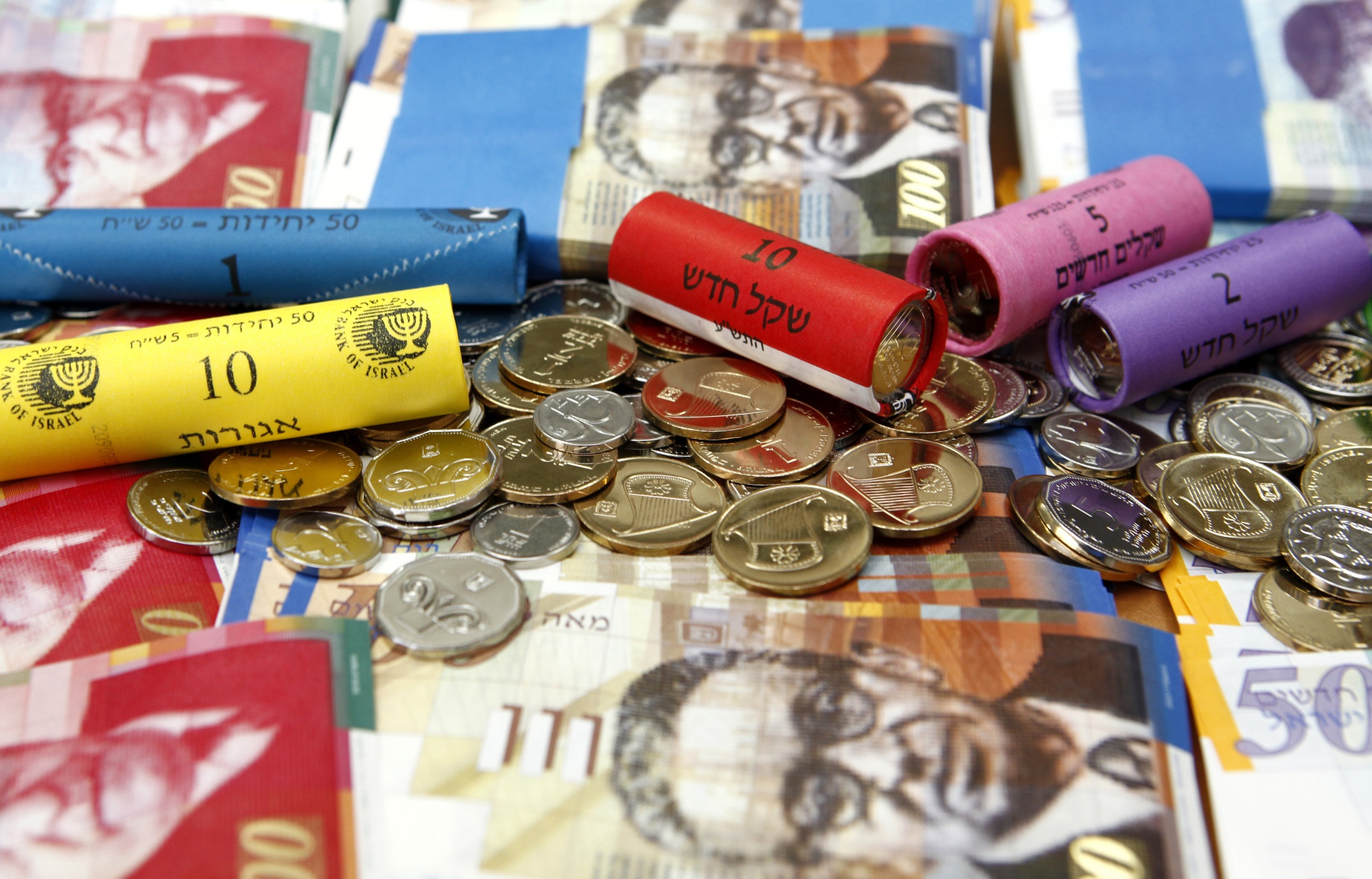Mixed denomination Shekel currency banknotes and tubes of coins