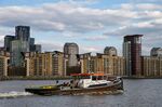 A boat on the River Thames passes residential apartments in London.&nbsp;
