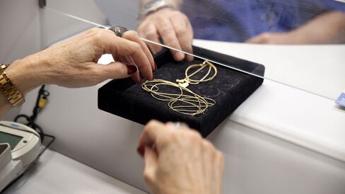 A customer passes jewelry to an appraiser at a government-run pawnshop in Rio de Janeiro.