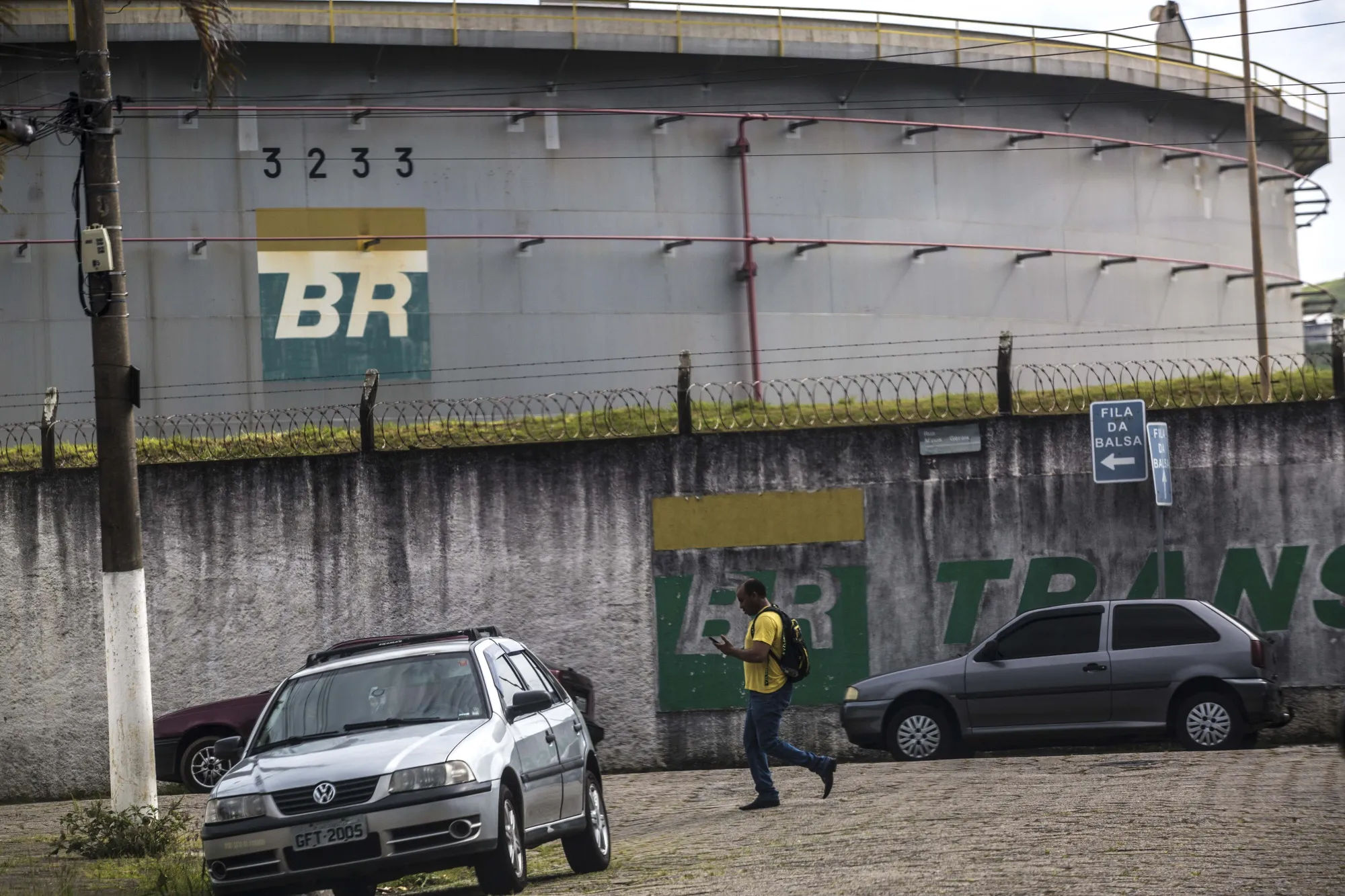 A man walks past an oil storage tank at the Petrobras Transporte SA (Transpetro) sea terminal in Sao Sebastiao, Sao Paulo state, Brazil.