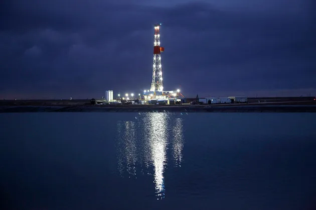 An oil rig reflected in a fracking pond on the Giddings Estate, a 10,000-acre field near Midland, Texas, owned by Pioneer Natural Resources on Feb. 15, 2012